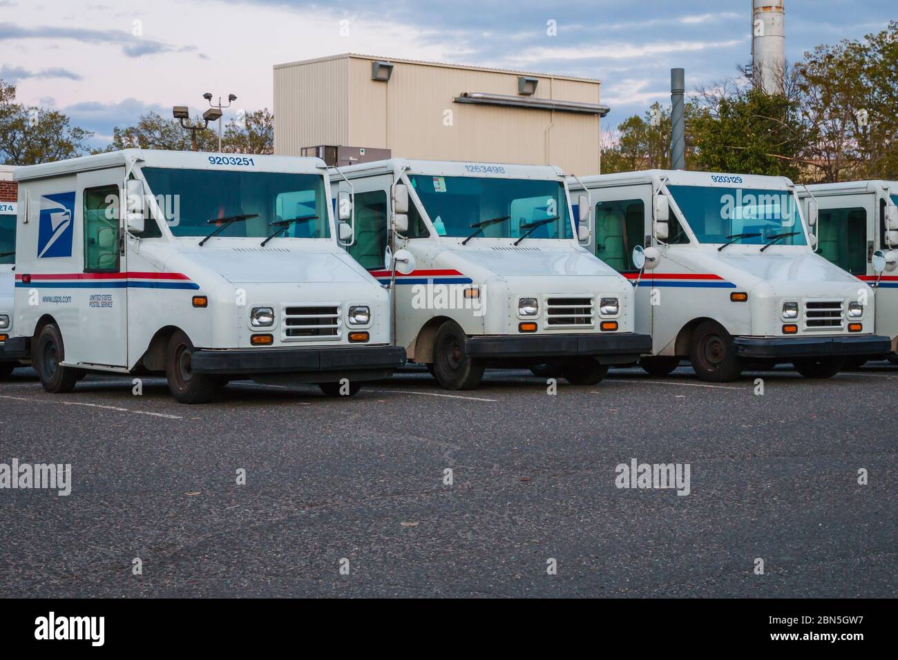 A number parked United States Postal Services vans in front of a Post Office Stock Photo