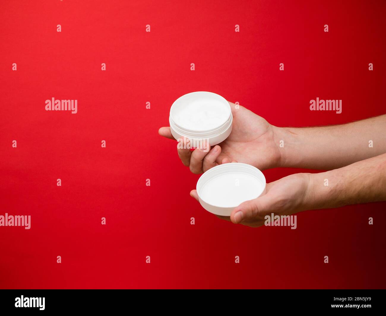 Male hand holding unbranded plastic tubewith white cream. Flacon for cream, toiletry. Bottle for professional cosmetics product. Skincare and beauty Stock Photo