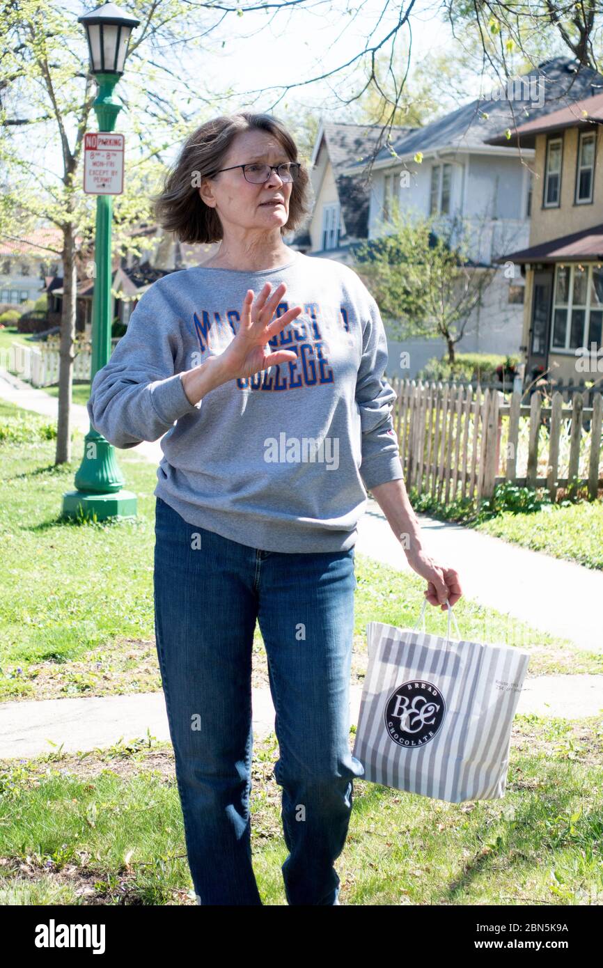Woman delivering a bag of goodies and expressing herself at a social distance during the covid-19 pandemic lockdown. St Paul Minnesota MN USA Stock Photo