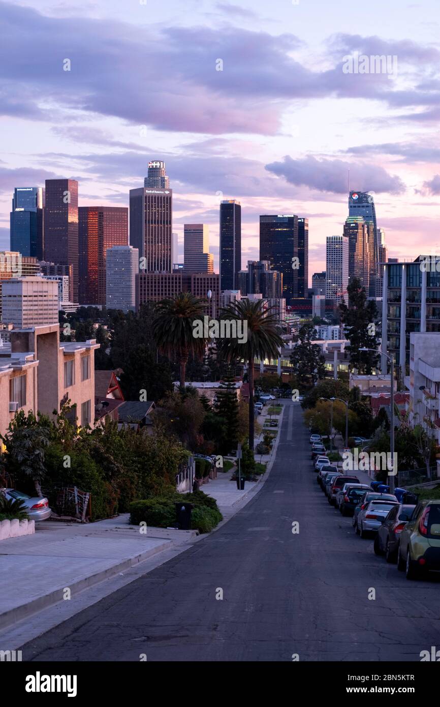 View looking down a hilly residential street in Los Angeles at sunset looking towards downtown LA Stock Photo