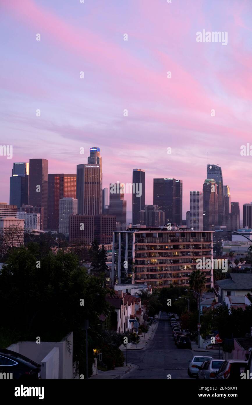 Looking down a street towards downtown Los Angeles skyline under a pink sky at sunset Stock Photo