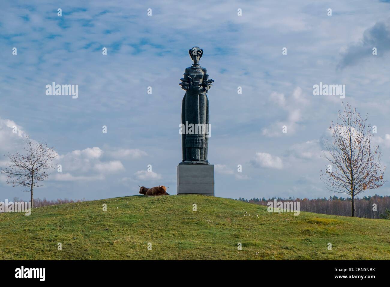 A huge bronze statue, perhaps Victory or Motherland, with a couple relaxing yaks. At Gruto Parkas near Druskininkai, Lithuania. Stock Photo