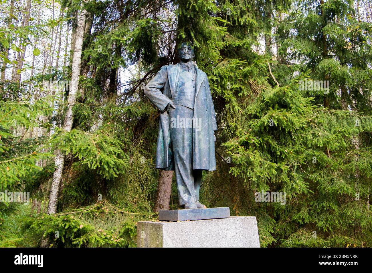 A large bronze statue of Lenin, partially obscured by trees. At Gruto Parkas near Druskininkai, Lithuania. Stock Photo
