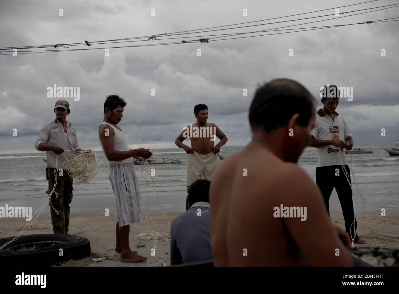 A fishing village in Sumatra west coast in December  Fishermen repairing fishing lines on the beach of Malabro village in Bengkulu, a city in Sumatra west coast facing Indian Ocean. Archival image. 1st December 2012. Stock Photo