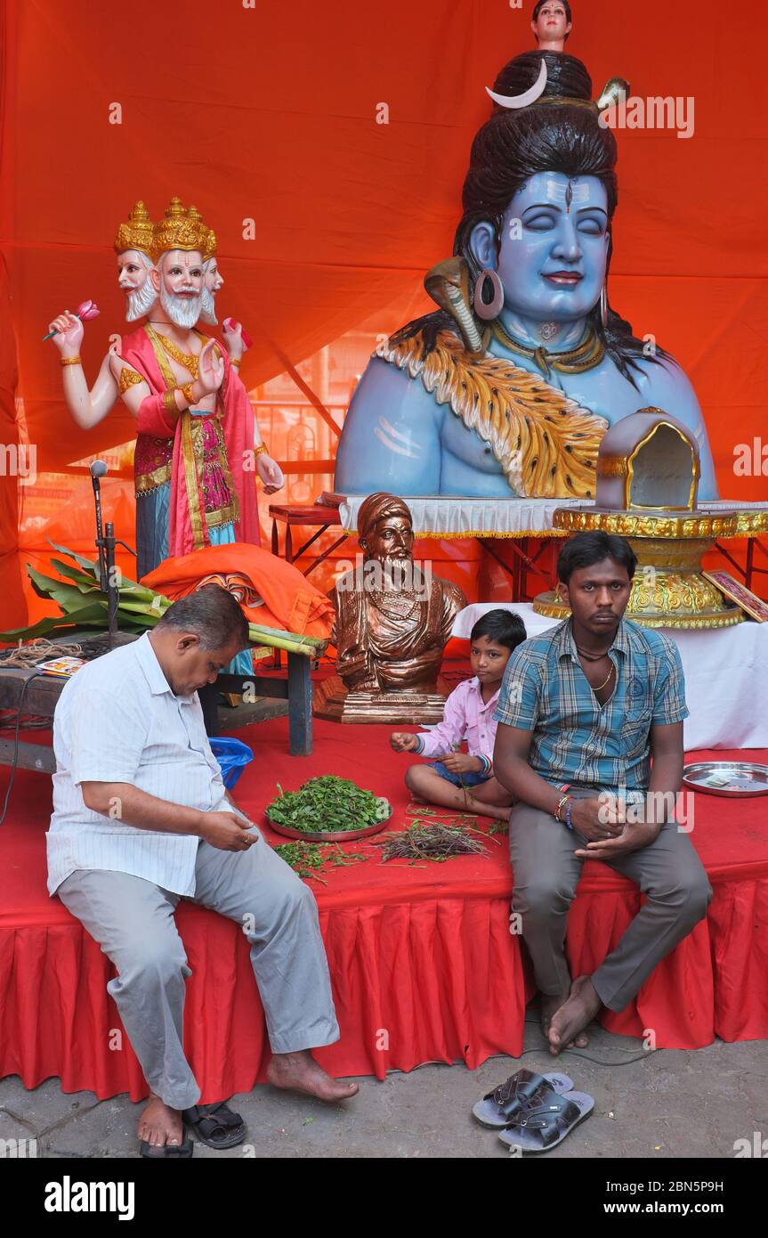 On a pandal (festive stage) for Hindu festival Mahashivratri, a Shiva statue stands near a bust of Shivaji Maharaj and a Brahma statue; Mumbai, India Stock Photo