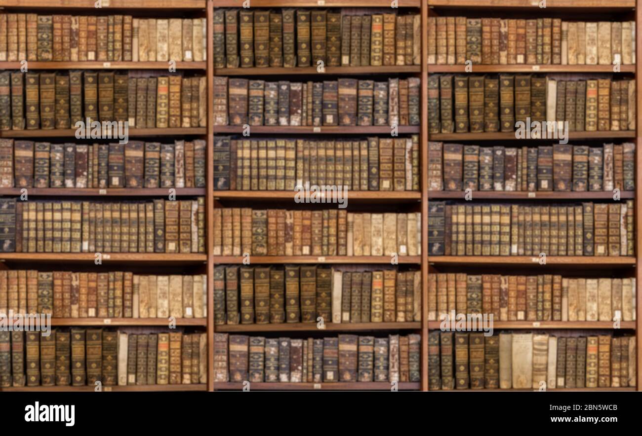 Defocused and blurred image of old antique library books on shelves for use in video conferencing background Stock Photo