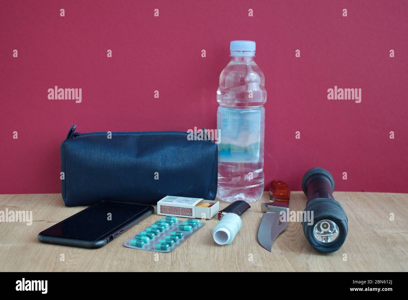 Emergency kit on wooden table against red wall Stock Photo