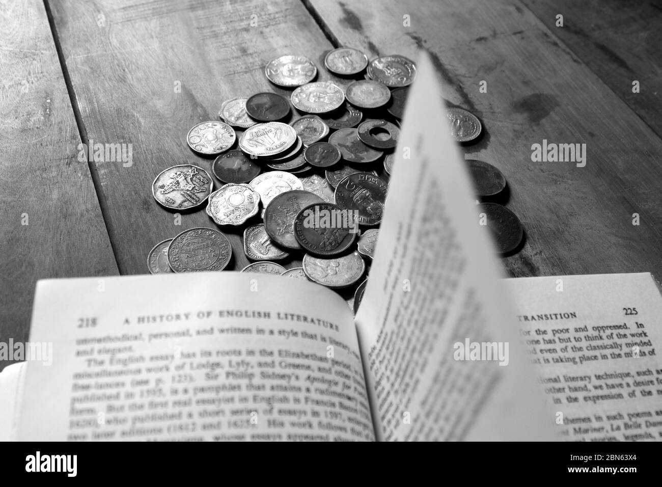 An old antique Indian paise coins in front of book. Old Indian vintage coins isolated on wooden background. Valid and invalid Indian currency. Stock Photo