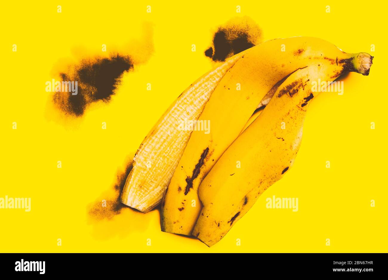 Flat lay template design, Peel big banana on the yellow stained paper, like black burns. The image has been adjusted to a bright yellow. Top view imag Stock Photo