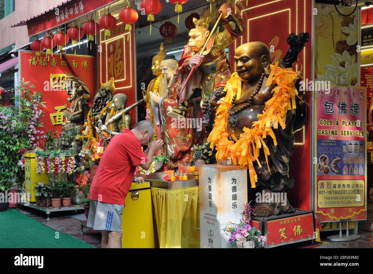 An ethnic Chinese worshipper bows in front of a statue of the Taoist