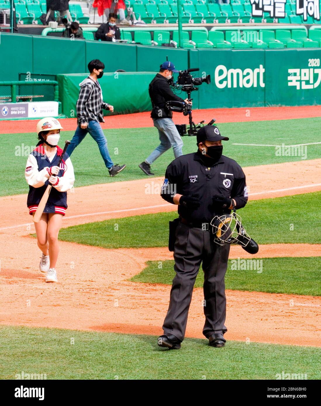 Home plate umpire, a bat girl and a TV crew wearing masks to prevent COVID19 infection, May 5