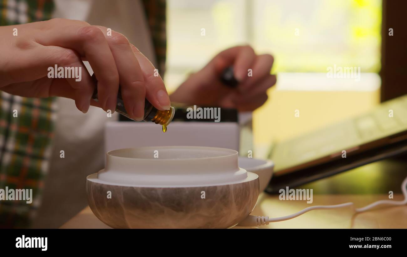 Woman adds essential oil into diffuser in kitchen Stock Photo Alamy