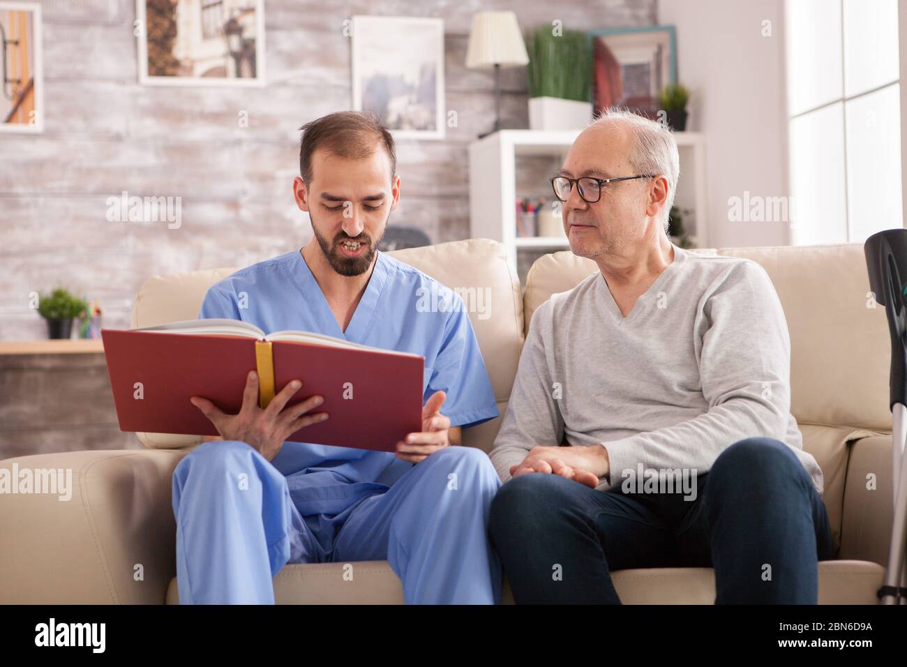 Happy senior woman in nursing home while doctor is reading a book Stock