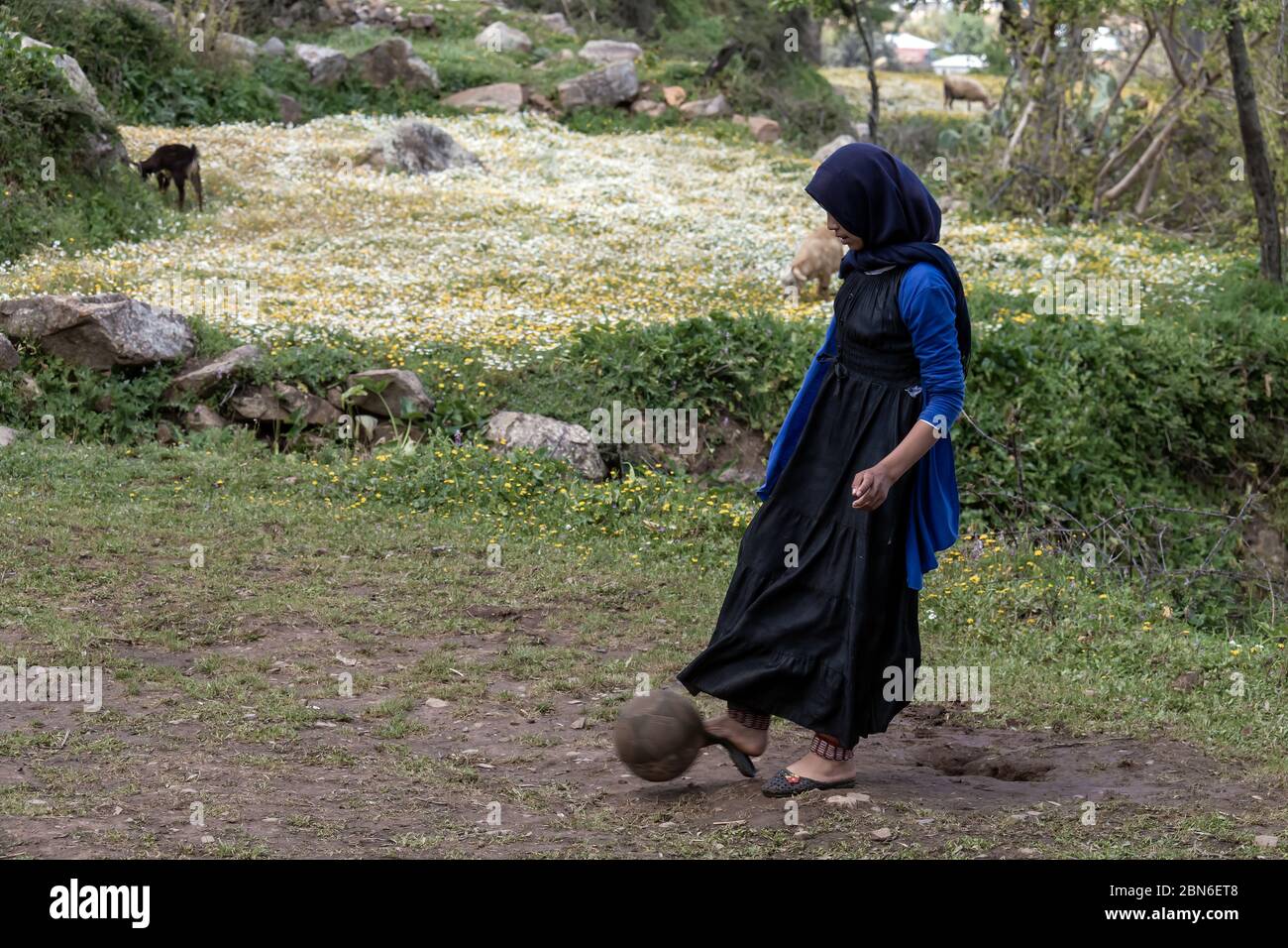 Rural area of Khizana, Chefchaouen, Morocco - April 19, 2018: A Moroccan girl playing football on the field Stock Photo