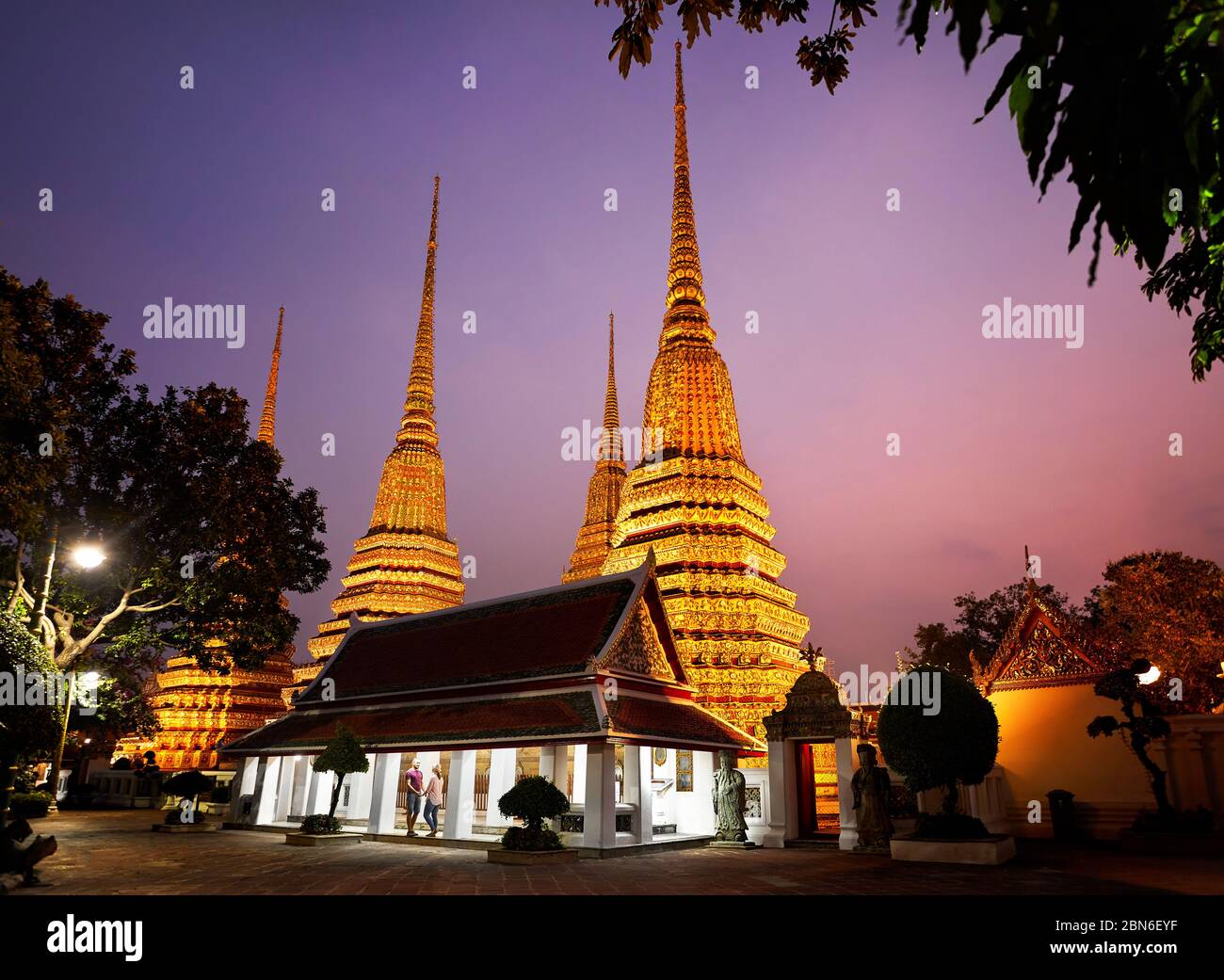 Tourist couple in the temple near golden Chedi of Wat Pho Temple in Bangkok at sunset sky, Thailand Stock Photo