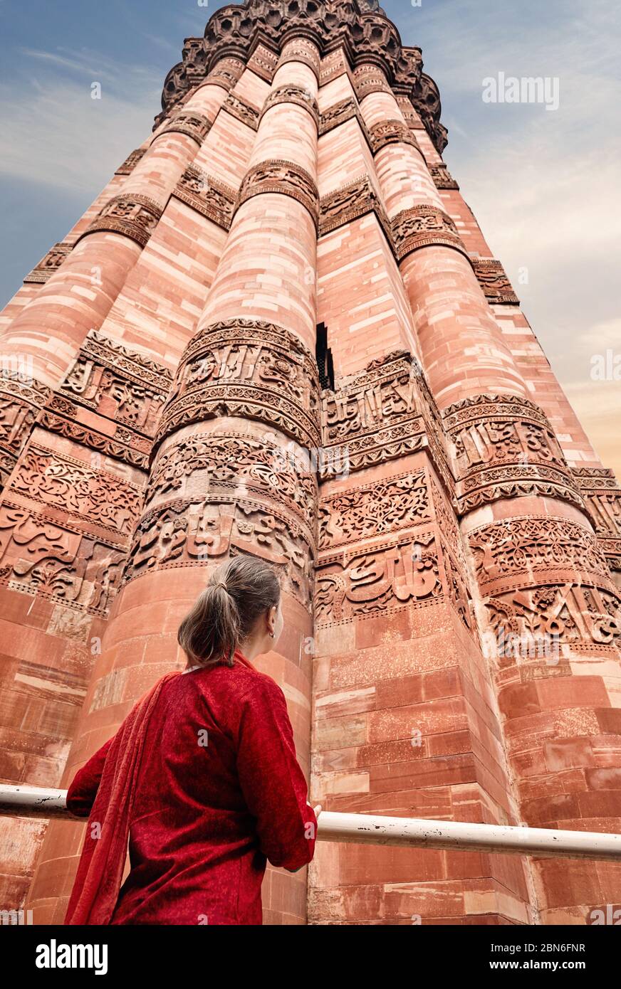 Woman in red costume is looking at Qutub Minar tower in Delhi, India Stock Photo
