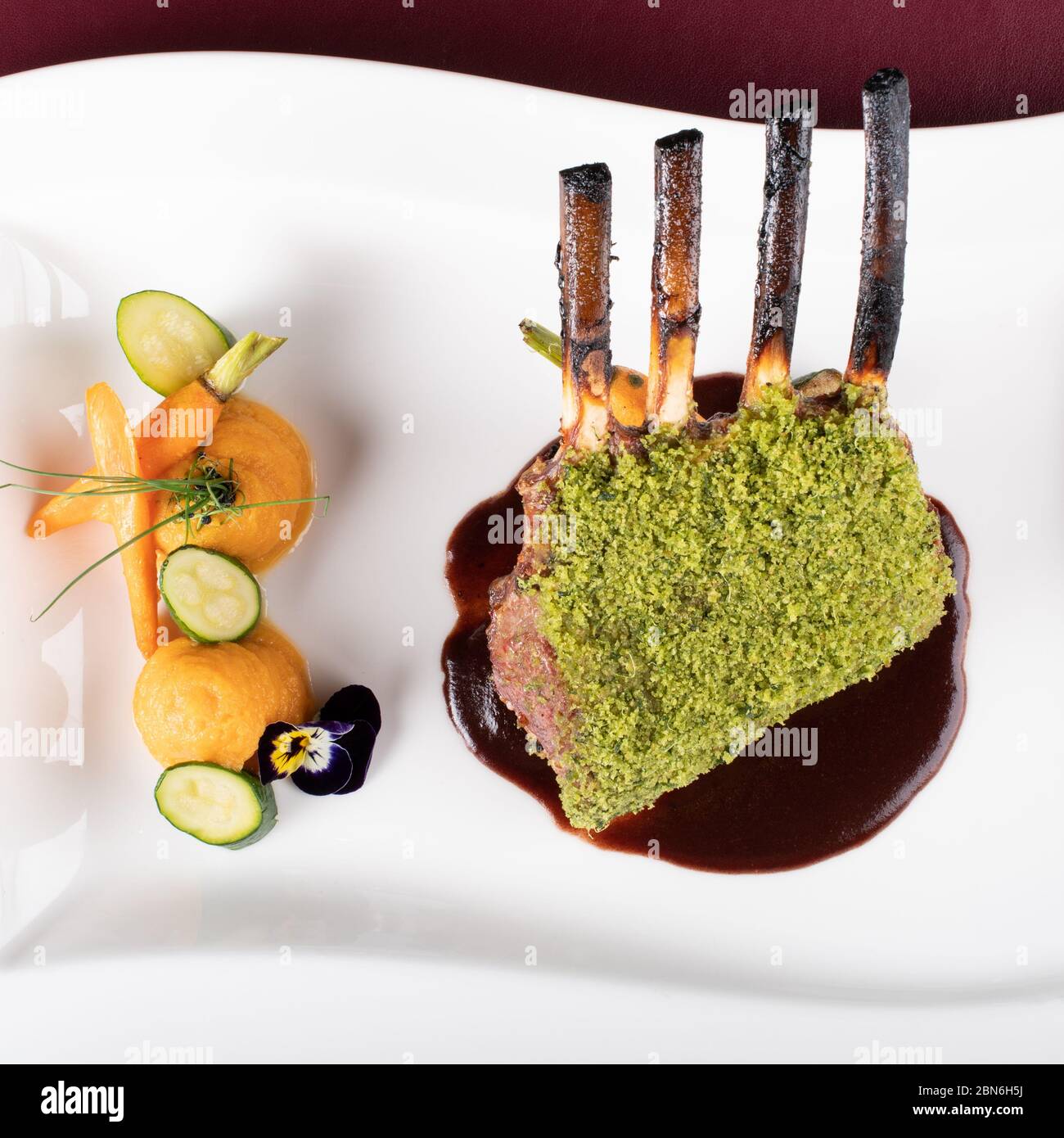Piece of lamb rack with bone roasted with green herb, bread, cheese ...