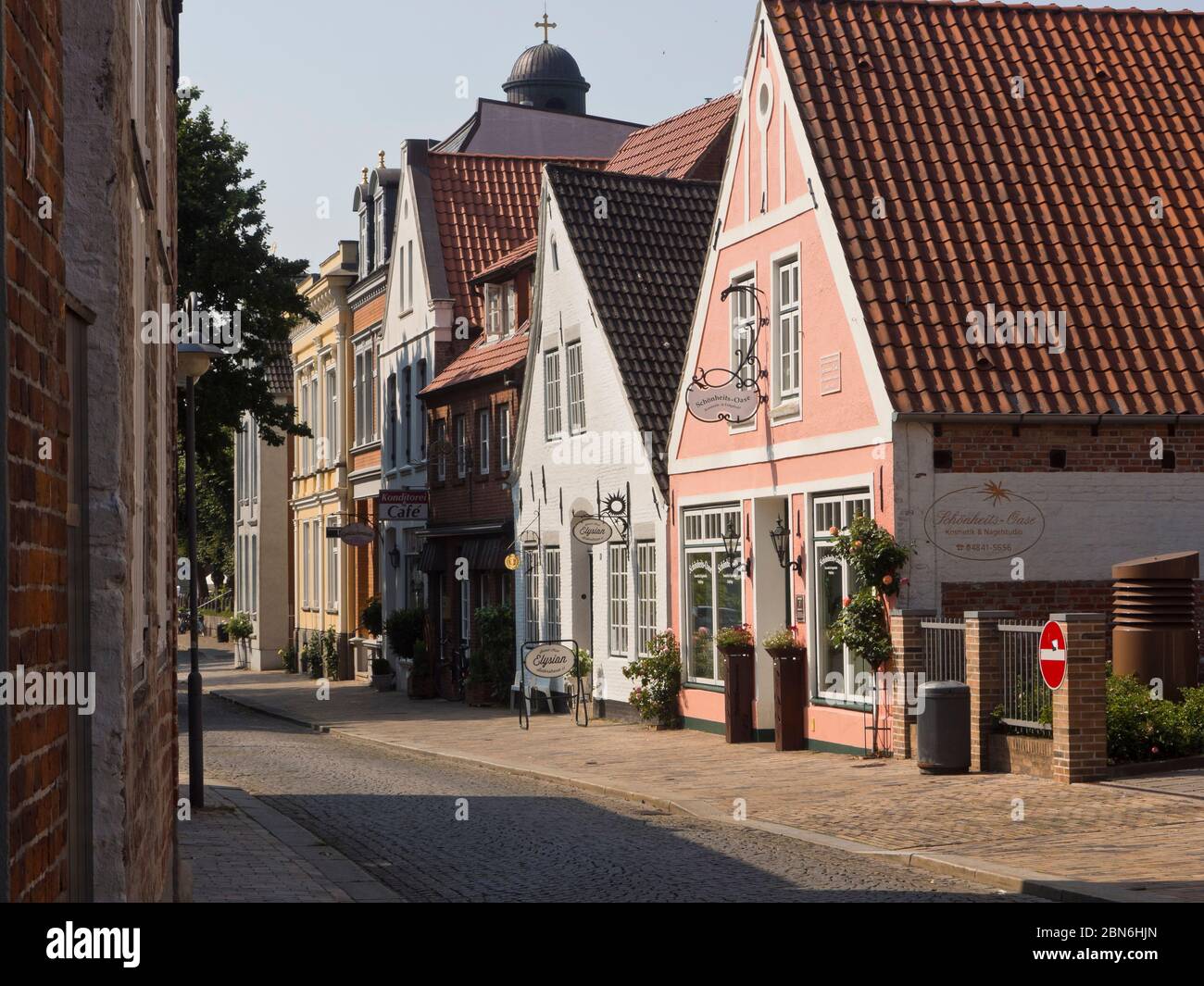 Idyllic narrow street with low houses and shops in the centre of Husum Schleswig-Holstein, Germany ideal for sightseeing on foot or by bike Stock Photo