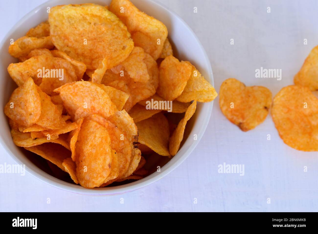 Closeup of potato chips or crisps in bowl against white background
