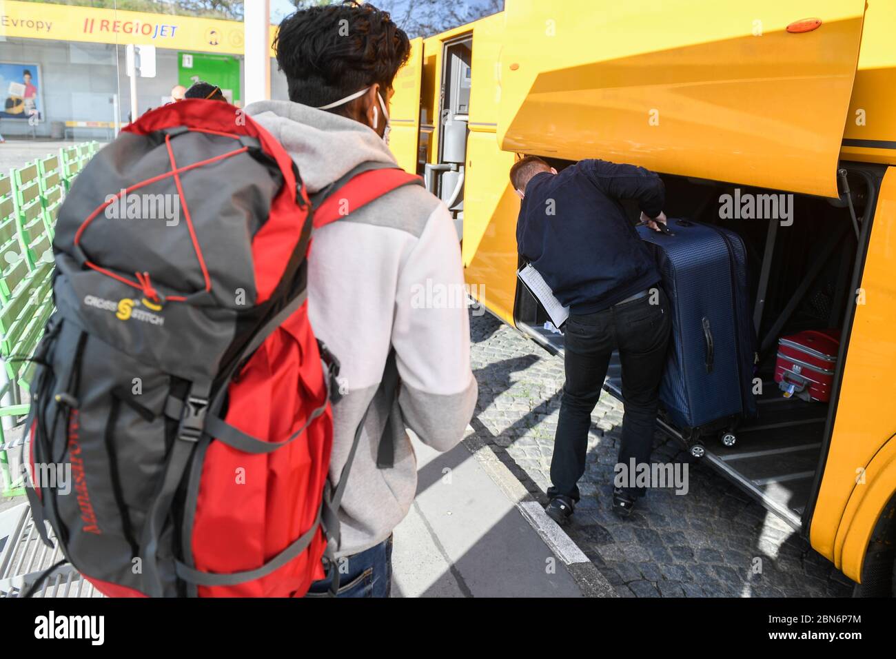 Prague, Czech Republic. 13th May, 2020. A driver, right, loads luggage into the first RegioJet bus, which left Prague for Germany after the permit of international passenger transport, on May 13, 2020, in Prague, Czech Republic. Thirteen people, mostly foreigners, traveled from Prague to Dresden and Berlin. This is the first renewed connection after the ban on international traffic due to the coronavirus pandemic. Credit: Michal Kamaryt/CTK Photo/Alamy Live News Stock Photo