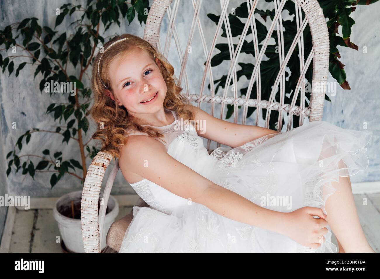 Beautiful little girl in white dress sits in vintage chair Stock Photo ...