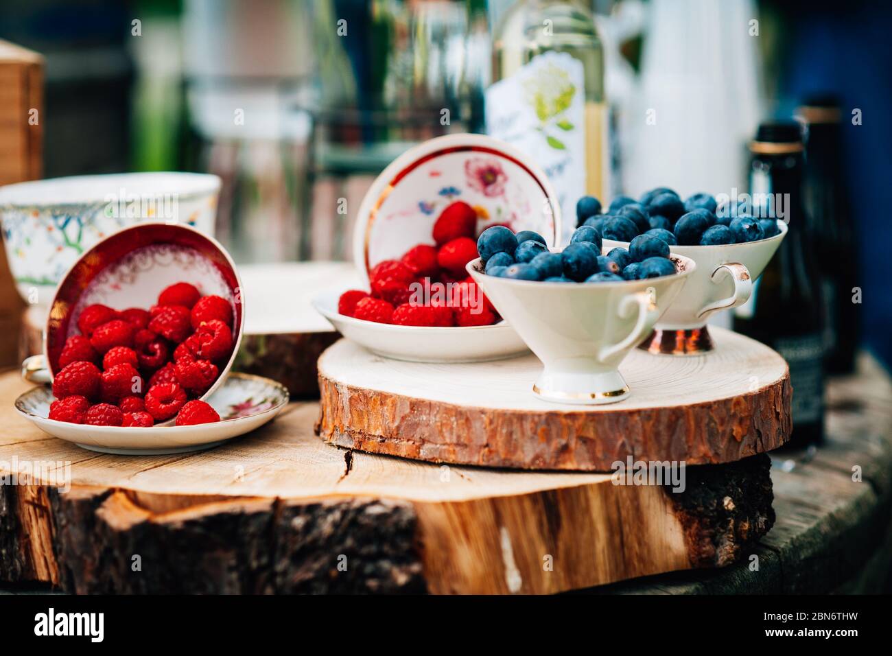 A table outdoors at a wedding with fresh summer berries in vintage cups and bowls. Blueberries and strawberries Stock Photo