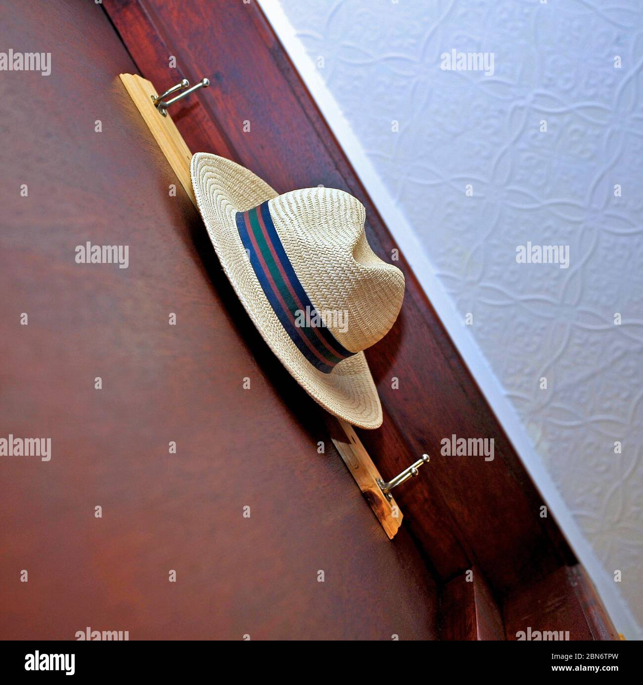 Straw hat hanging on hook on door Stock Photo