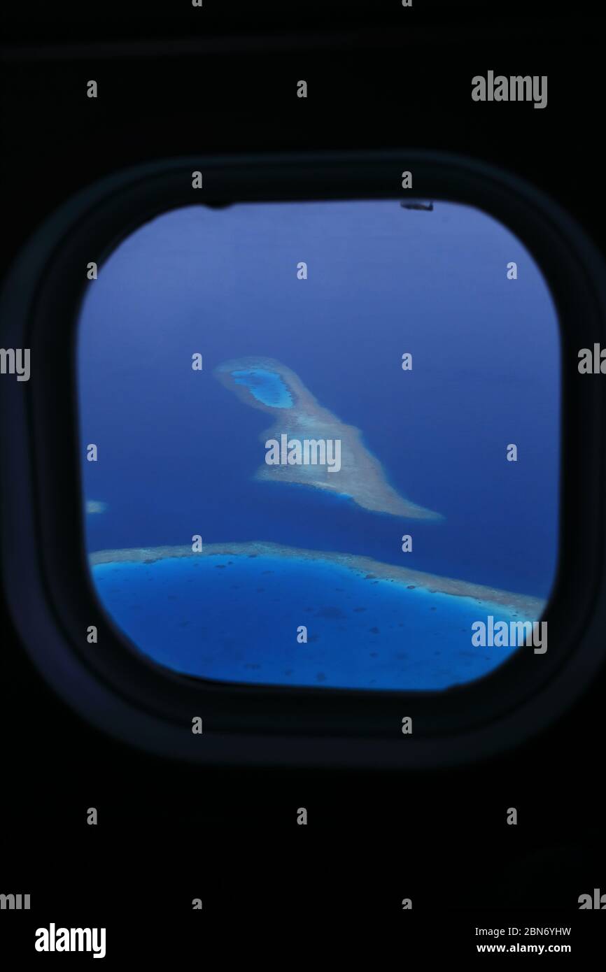 Aerial view through airplane windows on coral reefs of the Maldives ...