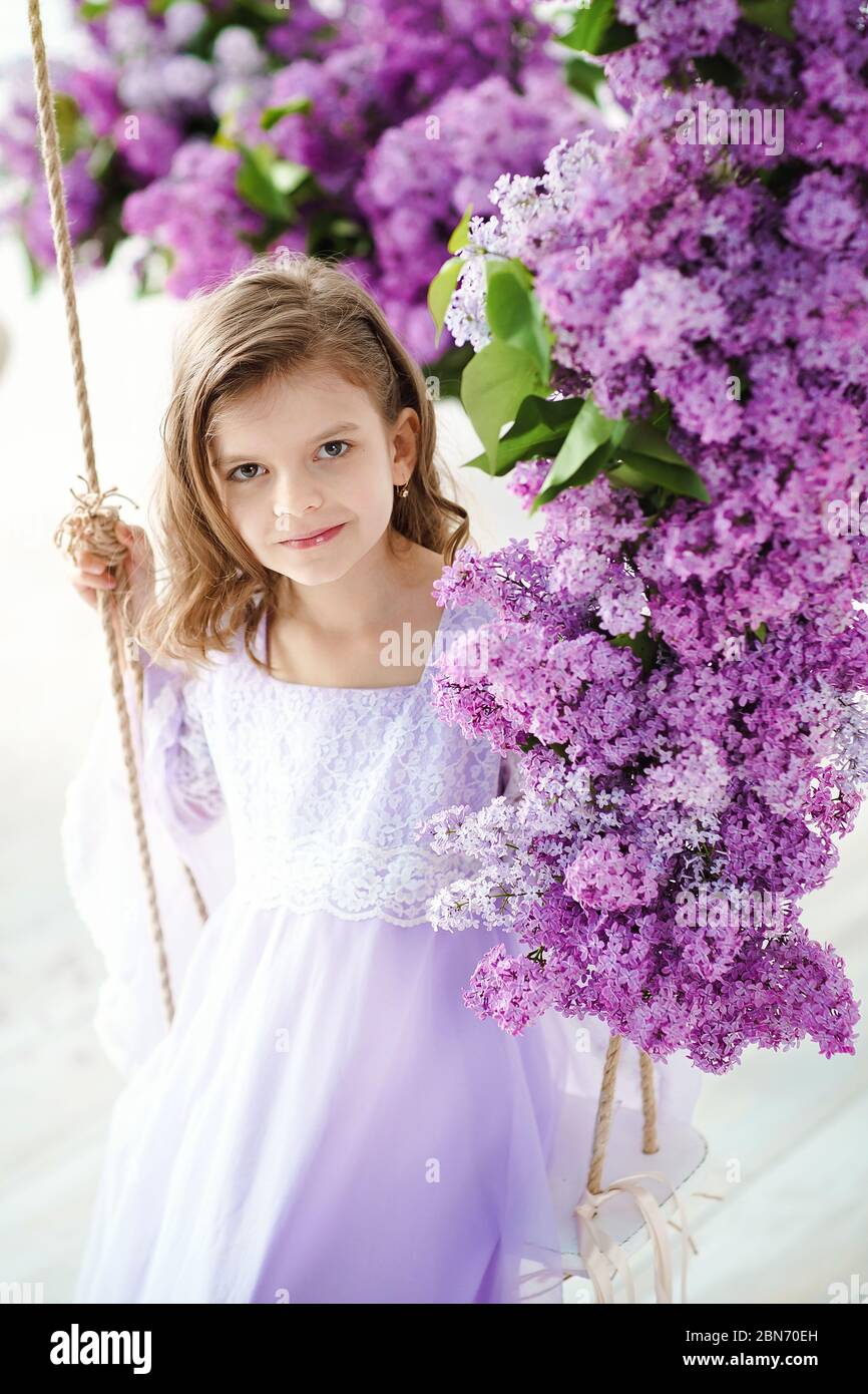Beautiful little girl of preschool age in a delicate dress sitting on a ...