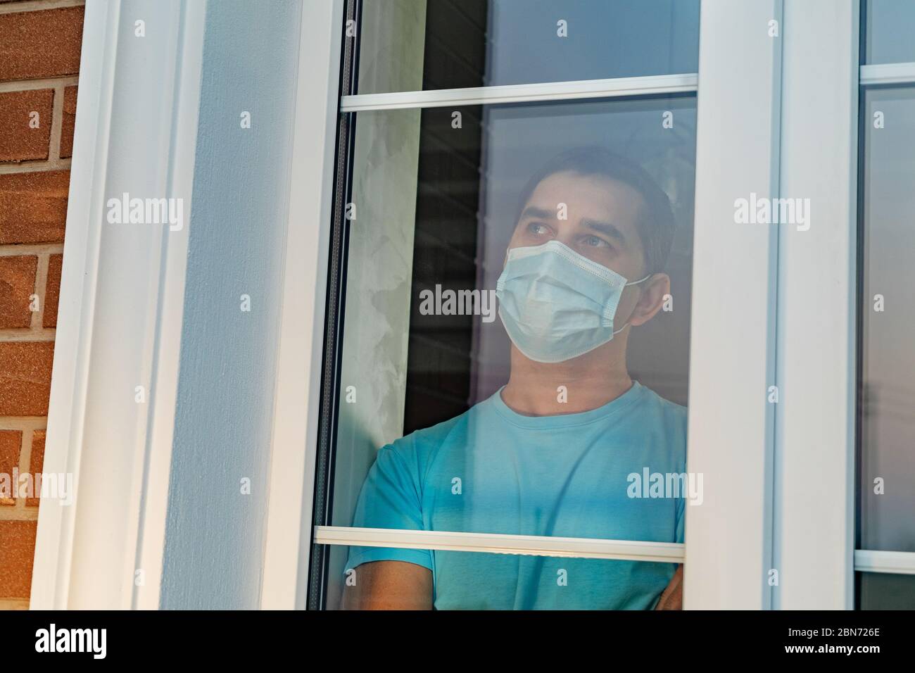 Infected man in medical mask on self-isolation Stock Photo