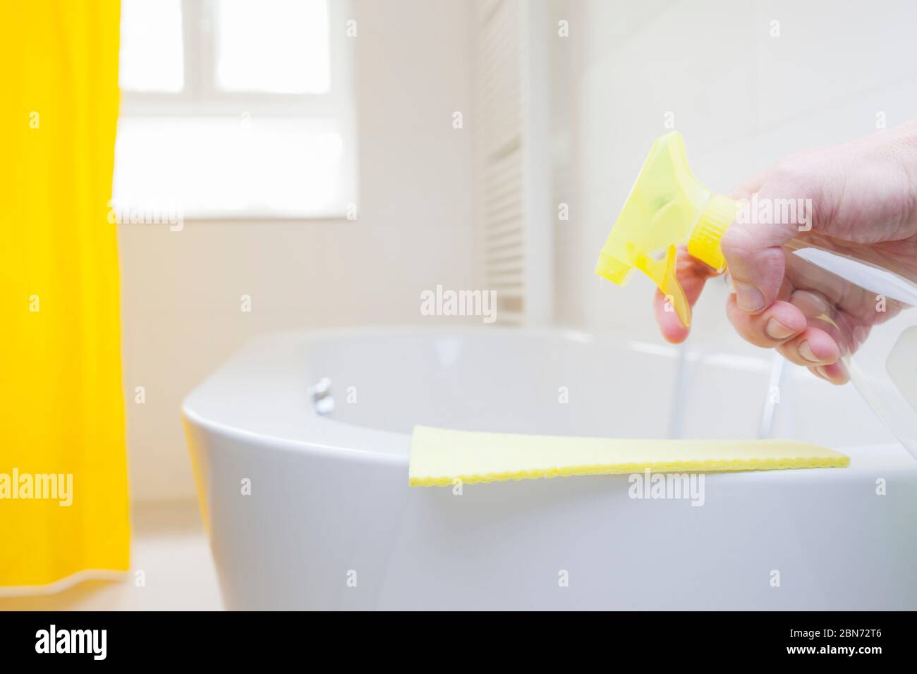 Hand spraying a detergent on a wipe in a bright bathroom focus on the