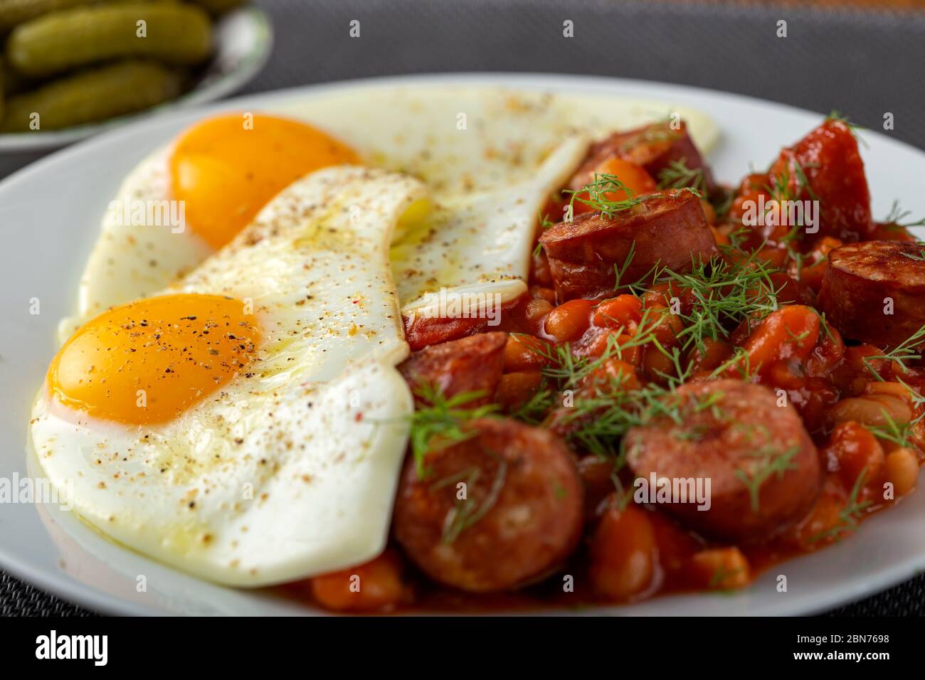 Fried eggs with beans and pork sausages - close up view Stock Photo