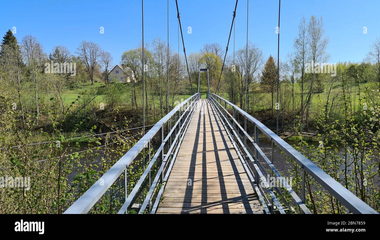 Suspension bridge over the river in spring Stock Photo