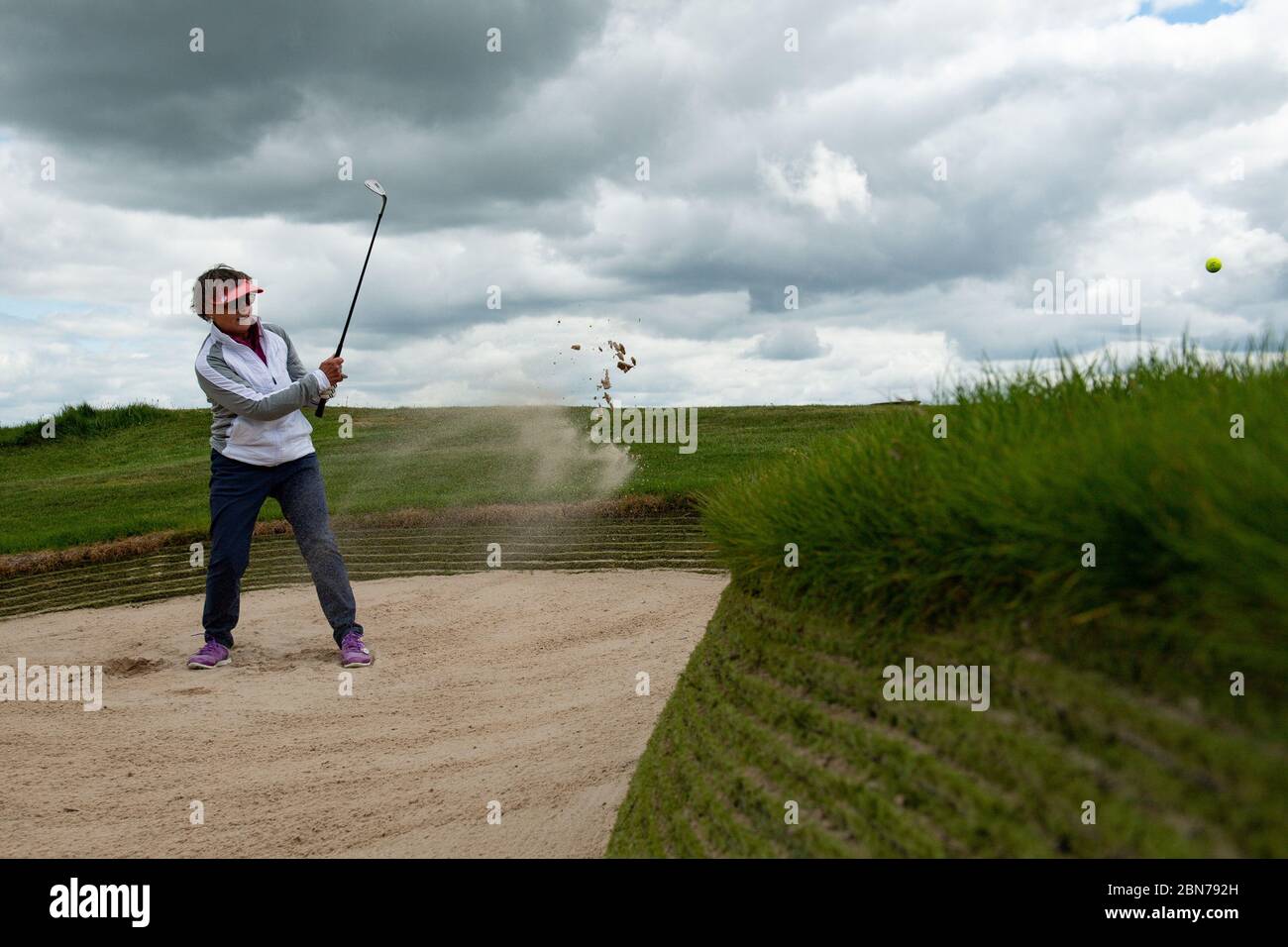 Annie Prince plays a bunker shot at Llanymynech Golf Club, Oswestry, where the course crosses the border of England and Wales. The course faces uncertainty as lockdown restrictions on golf are lifted in England from today, but remain in force in Wales. Stock Photo