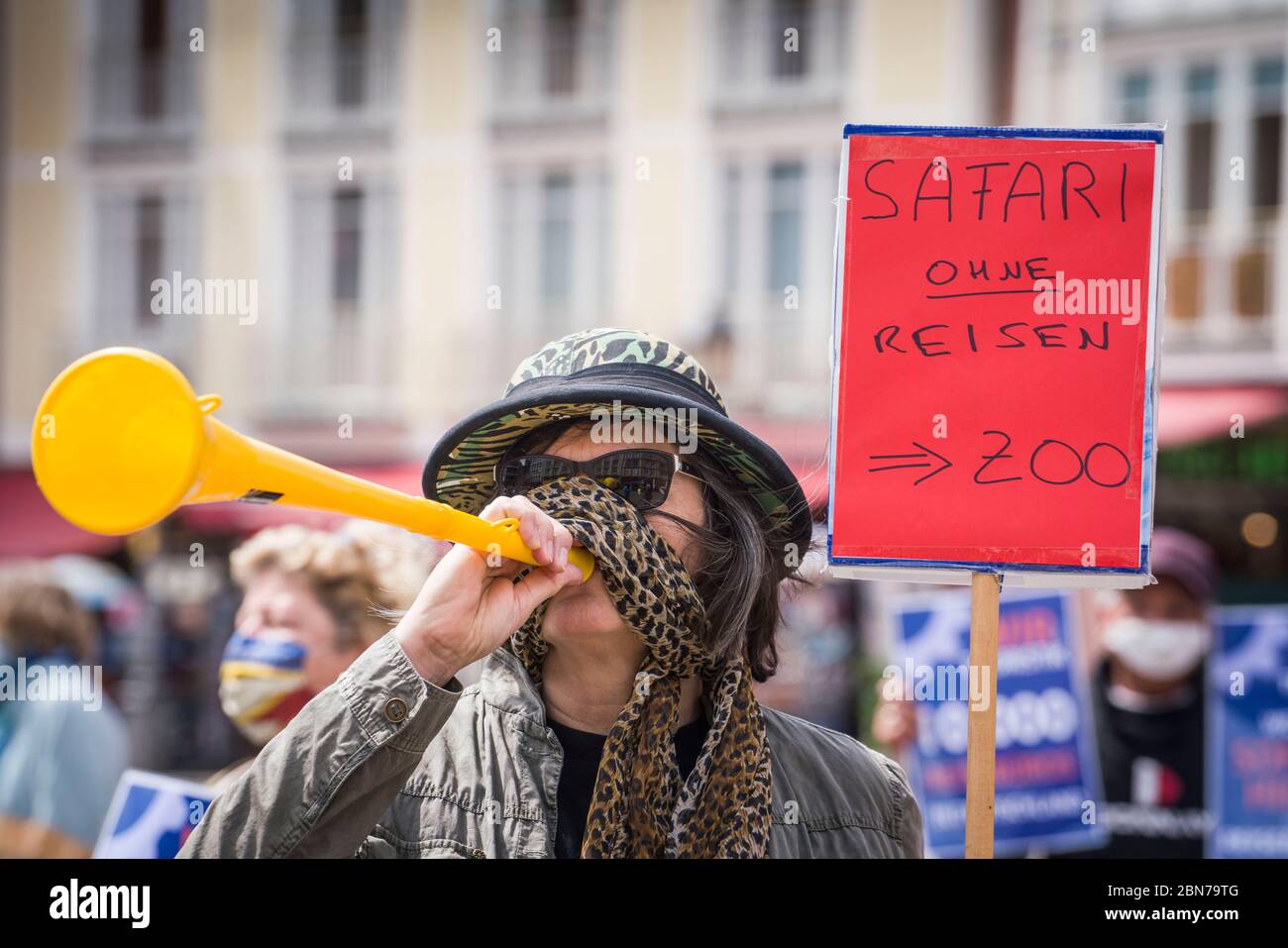13 May 2020, Hessen, Frankfurt/Main: A woman with a safari hat and a vuvuzela is standing in front of the Roman in a demonstration of owners of travel agencies and medium-sized tour operators with a poster saying 'Safari without travel = Zoo'. The demonstrators are calling for a special federal fund to handle repayments for cancelled trips. This is intended to secure jobs in travel agencies and at tour operators. Photo: Frank Rumpenhorst/dpa Stock Photo