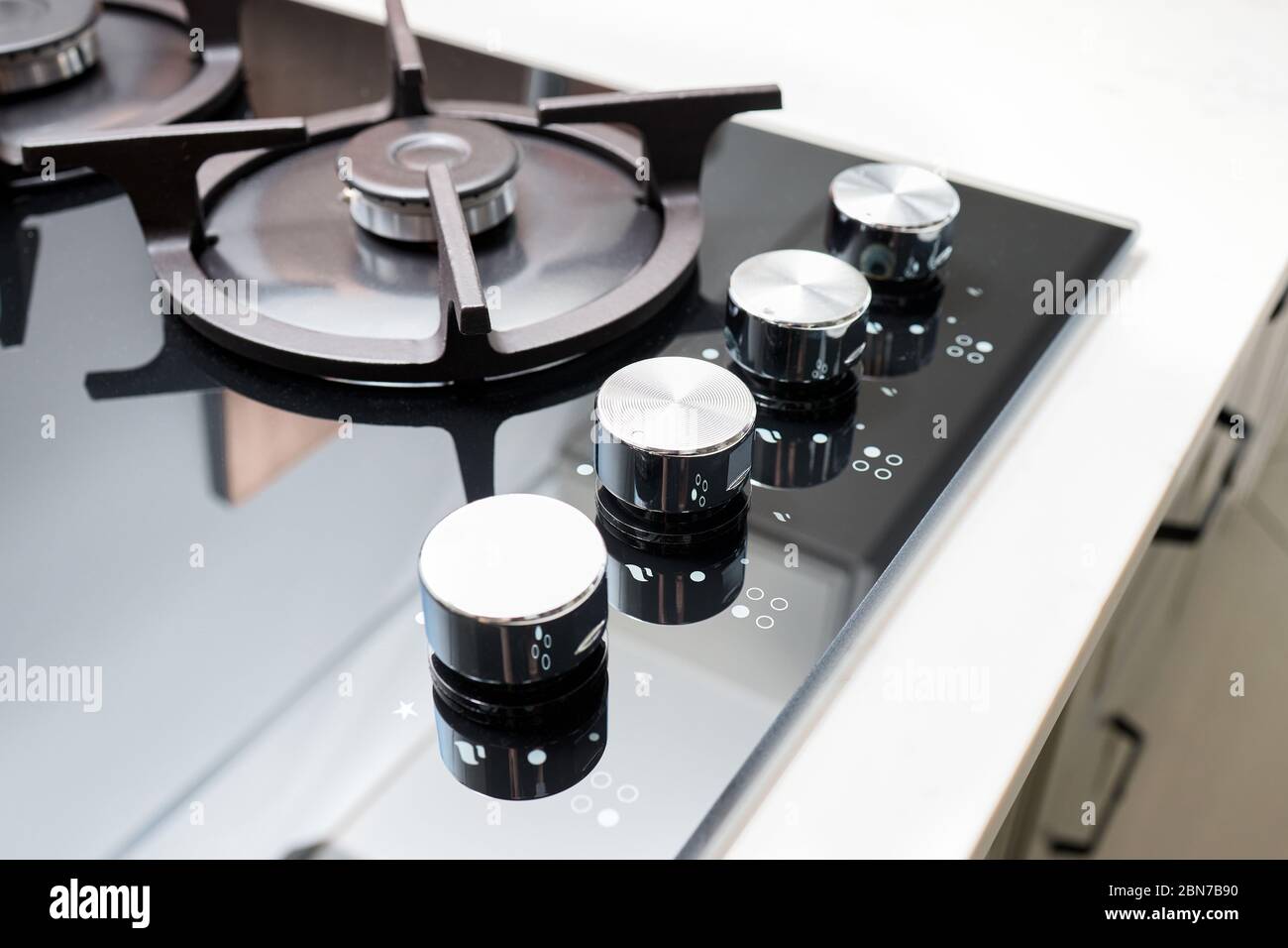 Hob cooker oven grill, stainless steel control knobs selective focus over out of focus kitchenware background. Stock Photo