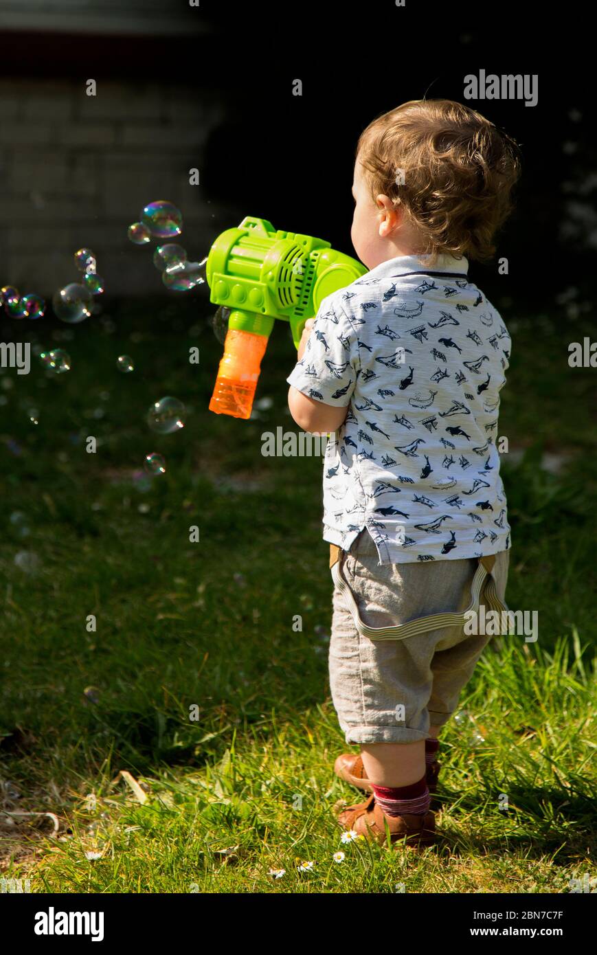 young boy playing with a bubble machine gun Stock Photo