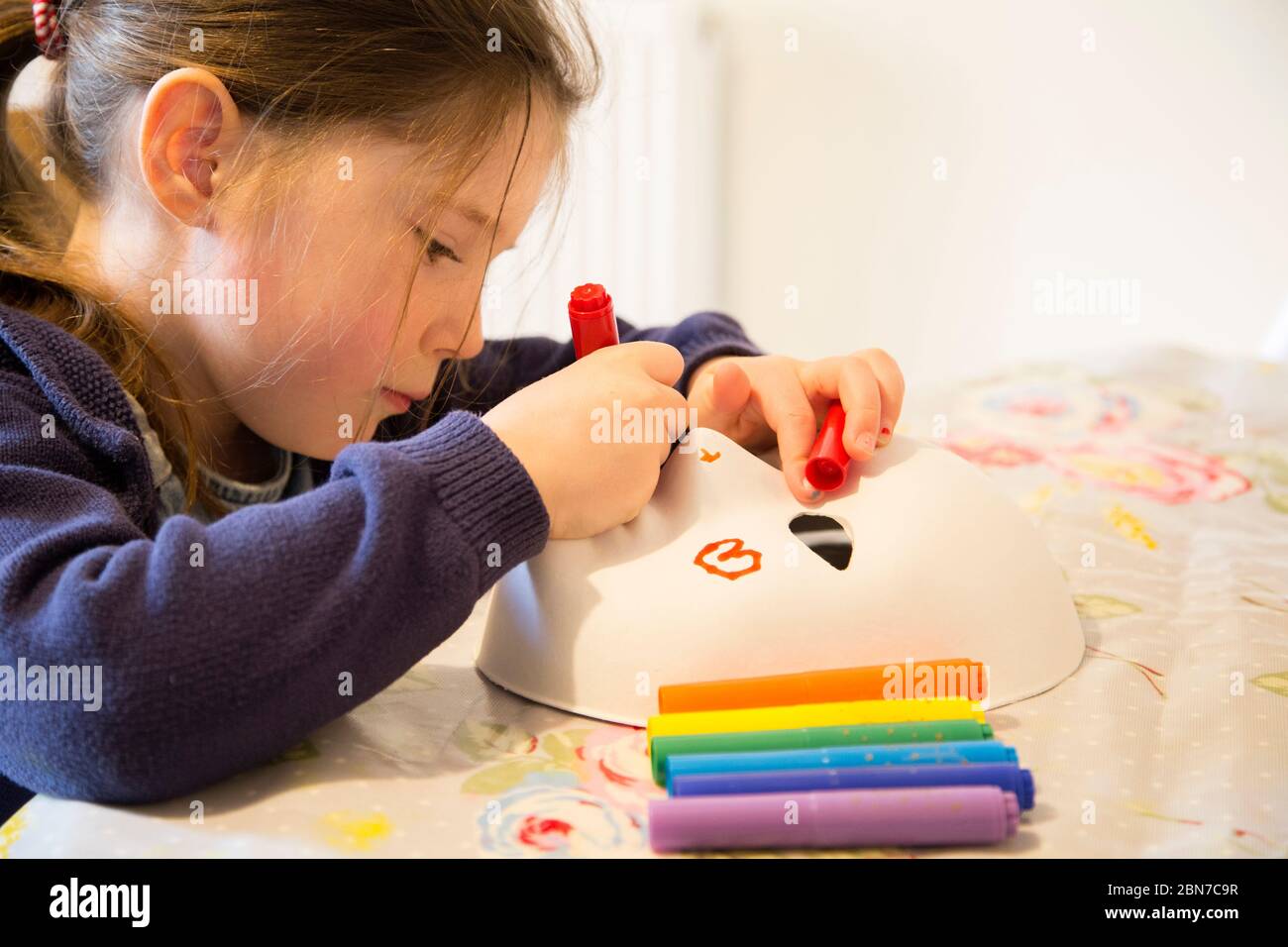 young girl drawing on a face mask Stock Photo