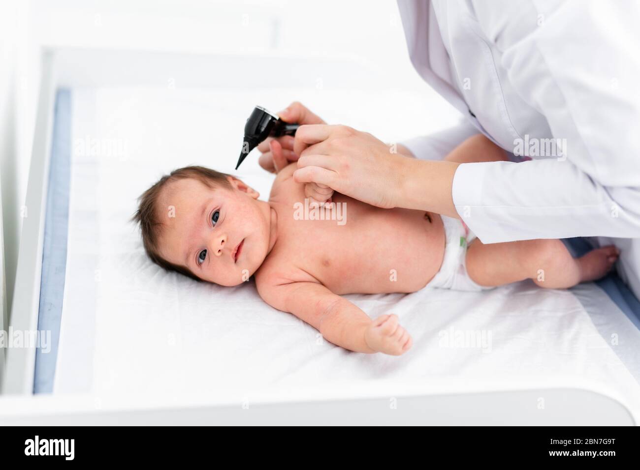 Pediatrician examines 2 week old baby's ear in new pediatric clinic