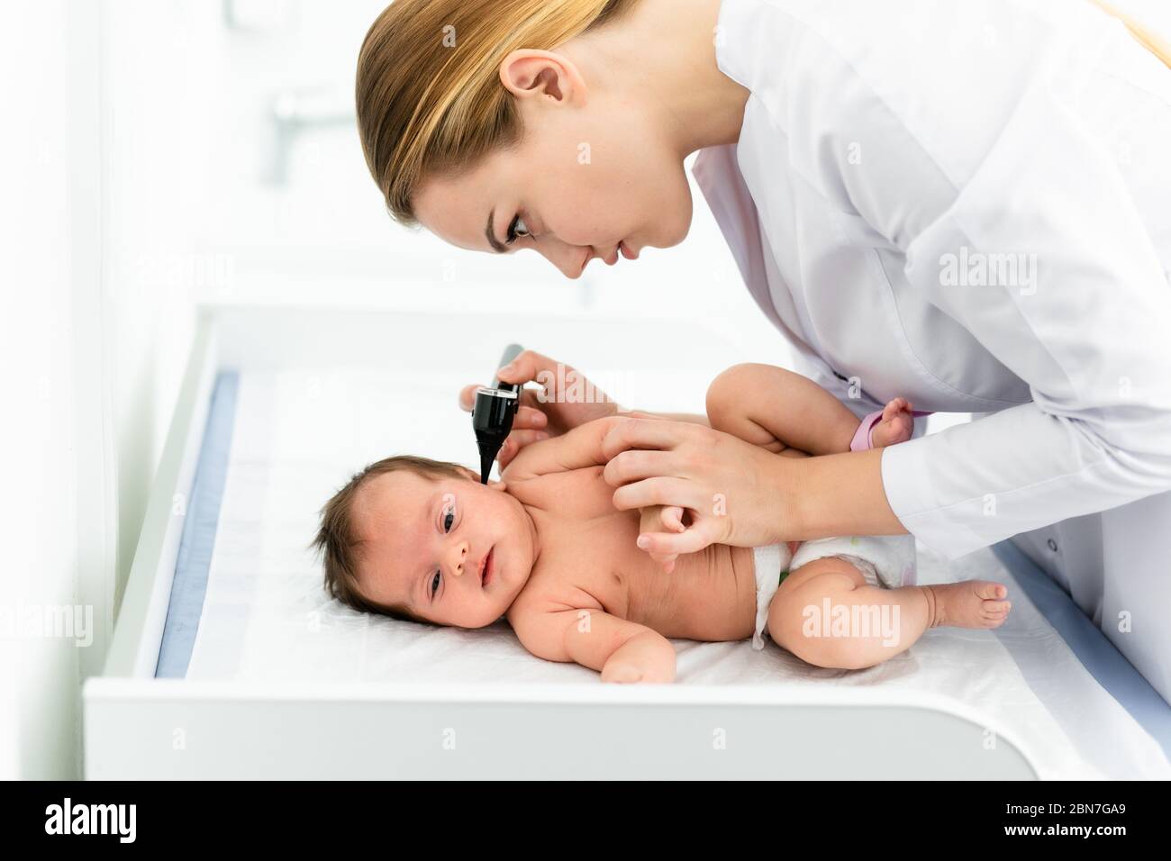 Pediatrician examines 2 week old baby's ear in new pediatric clinic