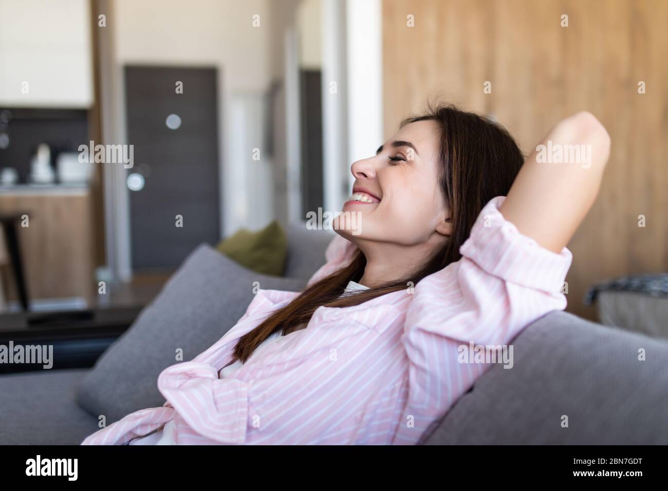 Closeup of a smiling young woman lying on couch Stock Photo - Alamy