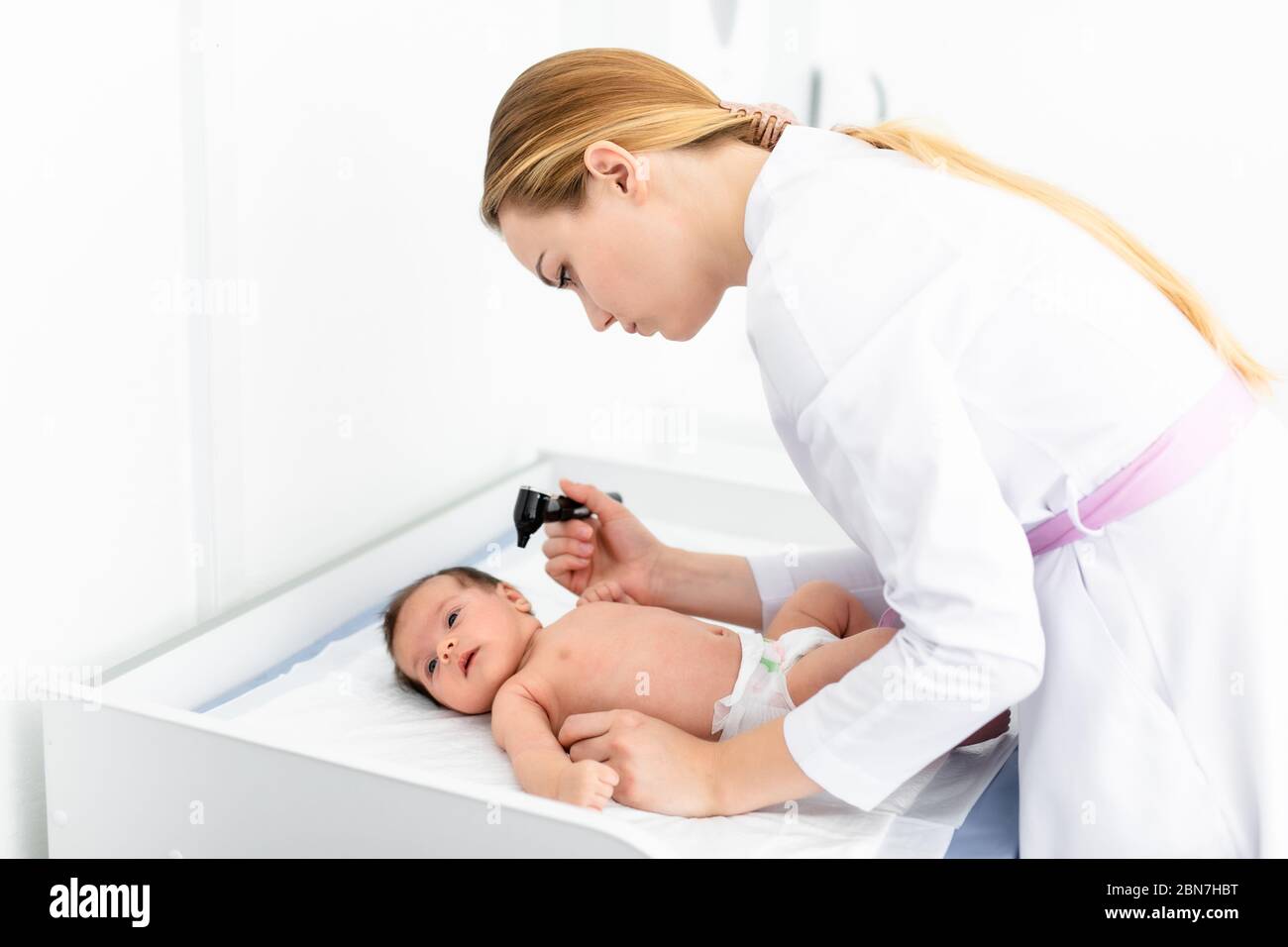Pediatrician examines 2 week old baby's ear in new pediatric clinic