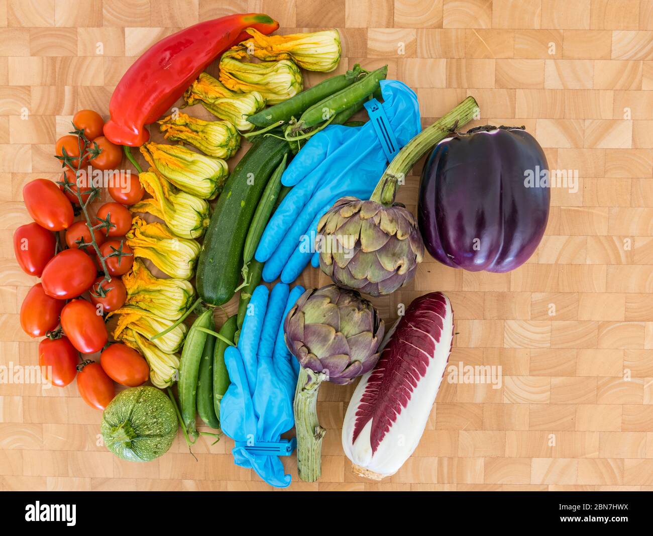 Rainbow of vegetables hope symbol Covid-19 Coronavirus pandemic: tomatoes, courgette flowers, peas, artichokes, endive, aubergine, surgical gloves Stock Photo