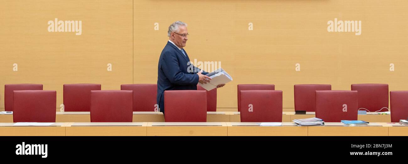 Munich, Germany. 13th May, 2020. Joachim Herrmann (CSU), Minister of the Interior of Bavaria, walks past the chairs during the session of the Bavarian parliament through the empty government bench. Topics of the session on 13.05.2020 include a change in the law on the use of health resort contributions for public transport and the current border controls in the wake of the Corona pandemic. Credit: Peter Kneffel/dpa/Alamy Live News Stock Photo