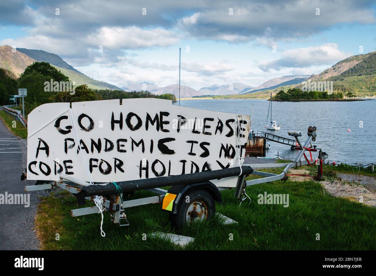 Sign painted at side of the road in Ballaculish, near Glencoe, Scotland, warning holiday makers and tourists to go home, during Corona Virus lockdown Stock Photo