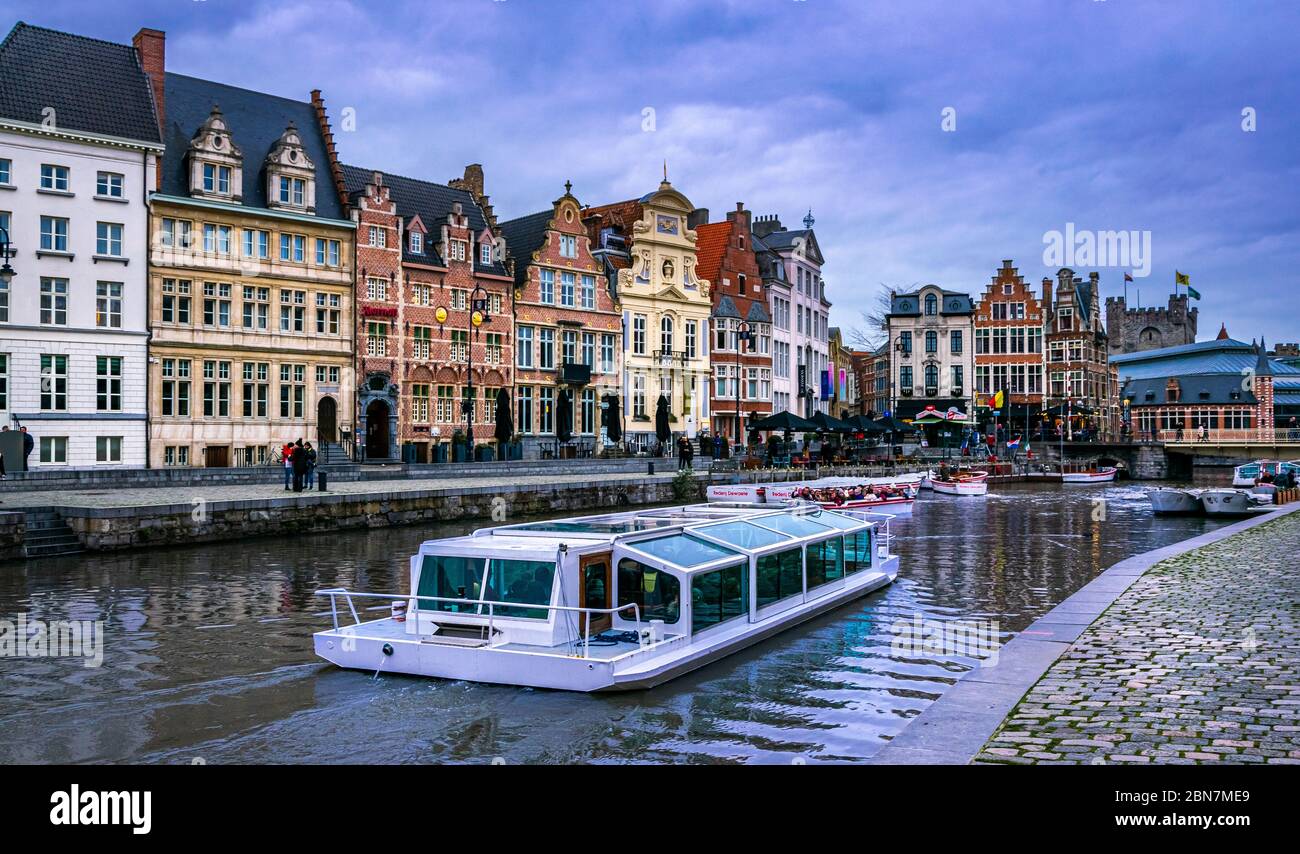 Touristic boat in the canals of Gent,Belgium. Beautiful old buildings on Korenlei embankment in Ghent, Belgium Stock Photo