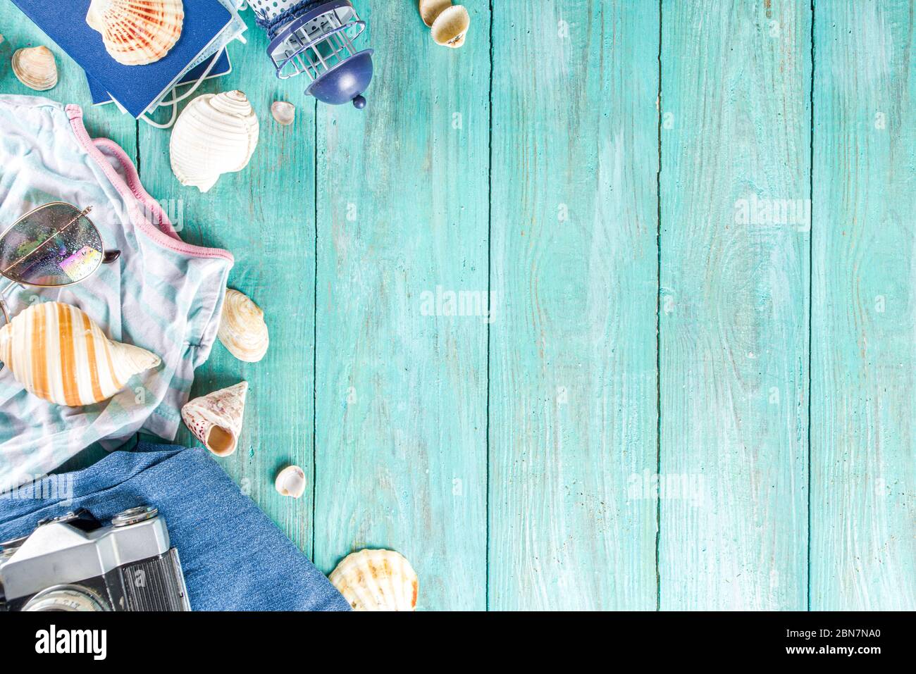 Bright  summer flat-lay background. Old blue wooden background with with summer woman clothes, sun glasses, hat, camera, passports and vacation ticket Stock Photo