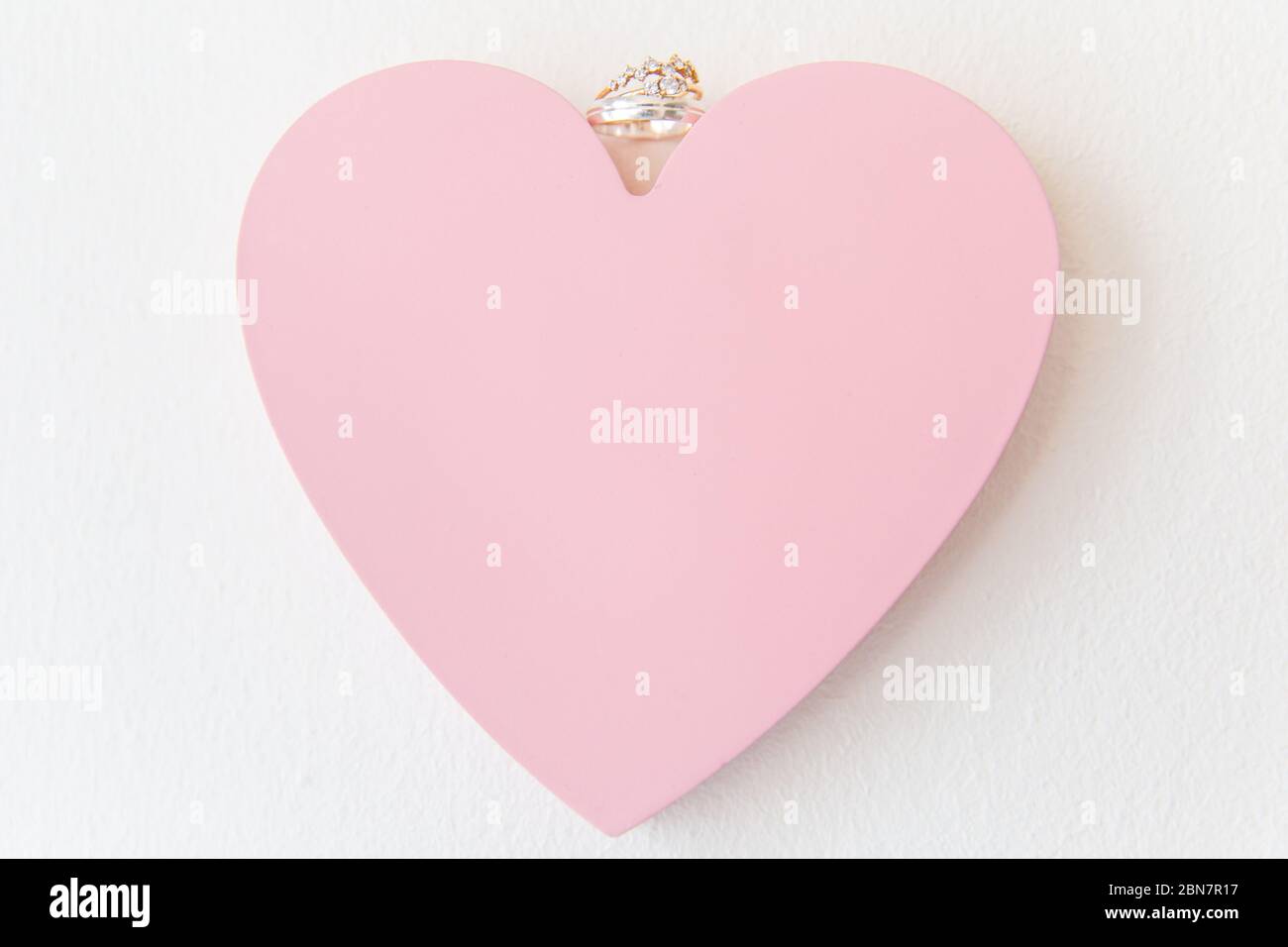 White Gold and Diamonds Wedding Rings on Pink Love Heart Stock Photo