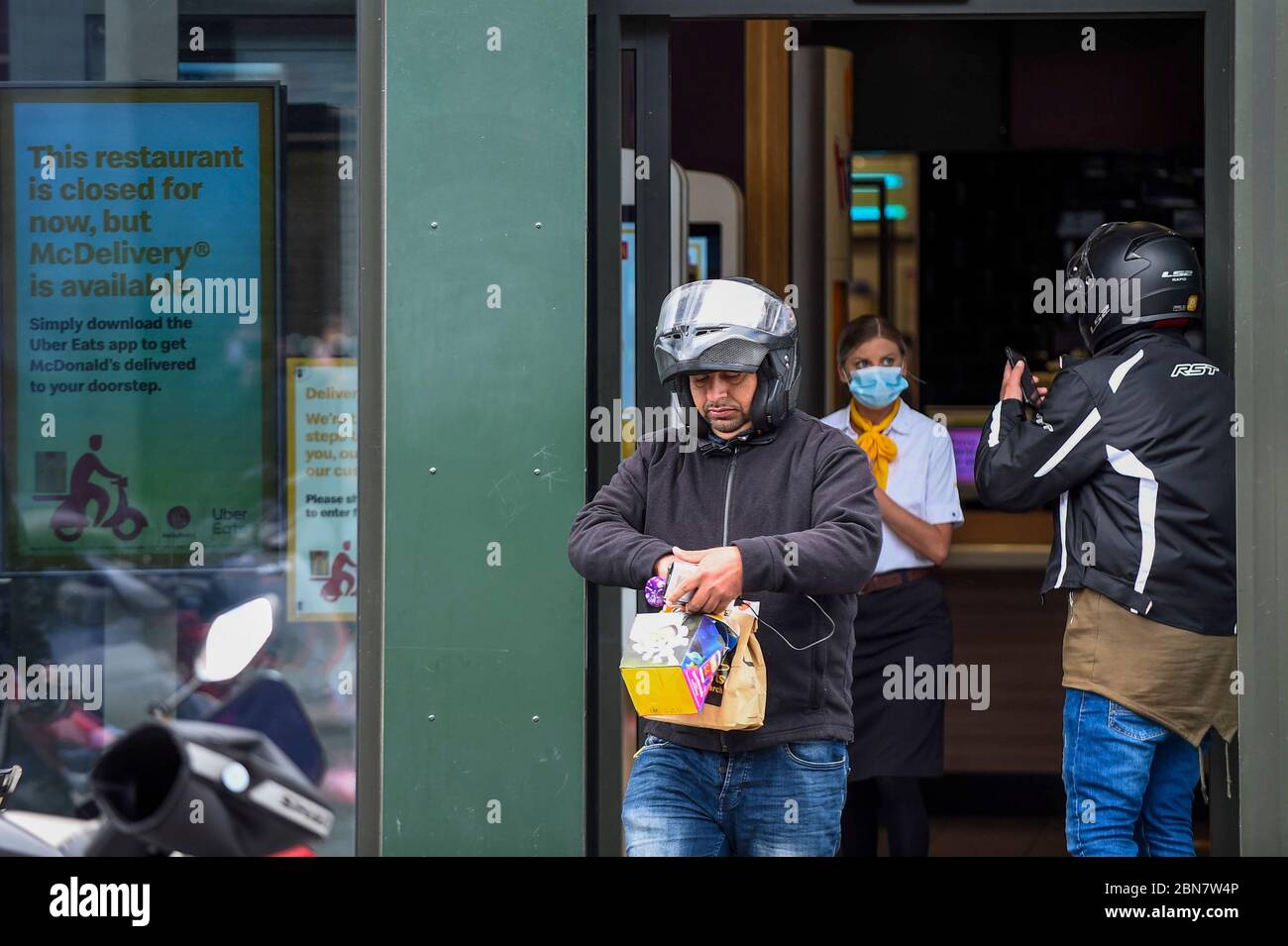 London, UK.  13 May 2020.  A delivery rider carries his order as the McDonald's fast food restaurant in Harrow reopens for 'McDelivery' during the ongoing coronavirus pandemic.  The restaurant is one of 14 in the UK that the chain is partially reopening with a limited menu and delivery only.  Delivery is satisfied by third parties such as Uber Eats and Deliveroo.  Credit: Stephen Chung / Alamy Live News Stock Photo