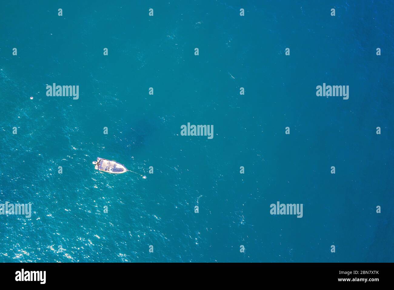 top view of a white boat anchored in the blue sea in a tropical beach ...